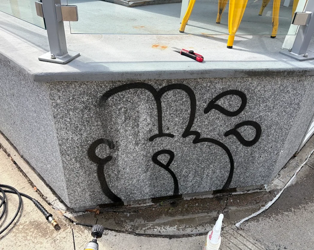 Graffiti noir sur le granite avant nettoyage à Trois-Rivières